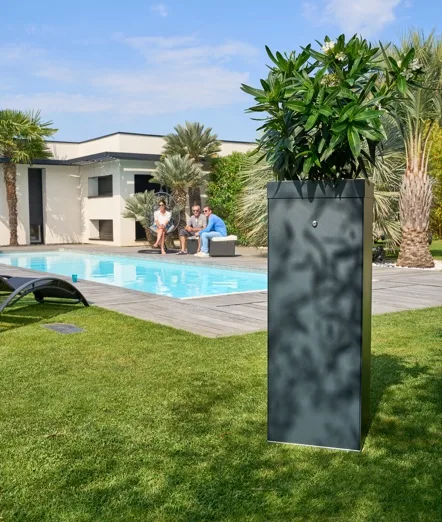 Photo de la borne anti-moustique de la marque Ma Boite à Moustique installée en extérieur avec en arrière plan des amis discutant au bord d'une piscine.